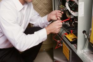 Close view on male HVAC technician's hands as he repairs a furnace.