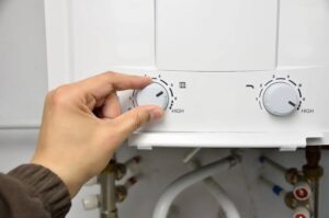 homeowner adjusting temperature setting on water heater