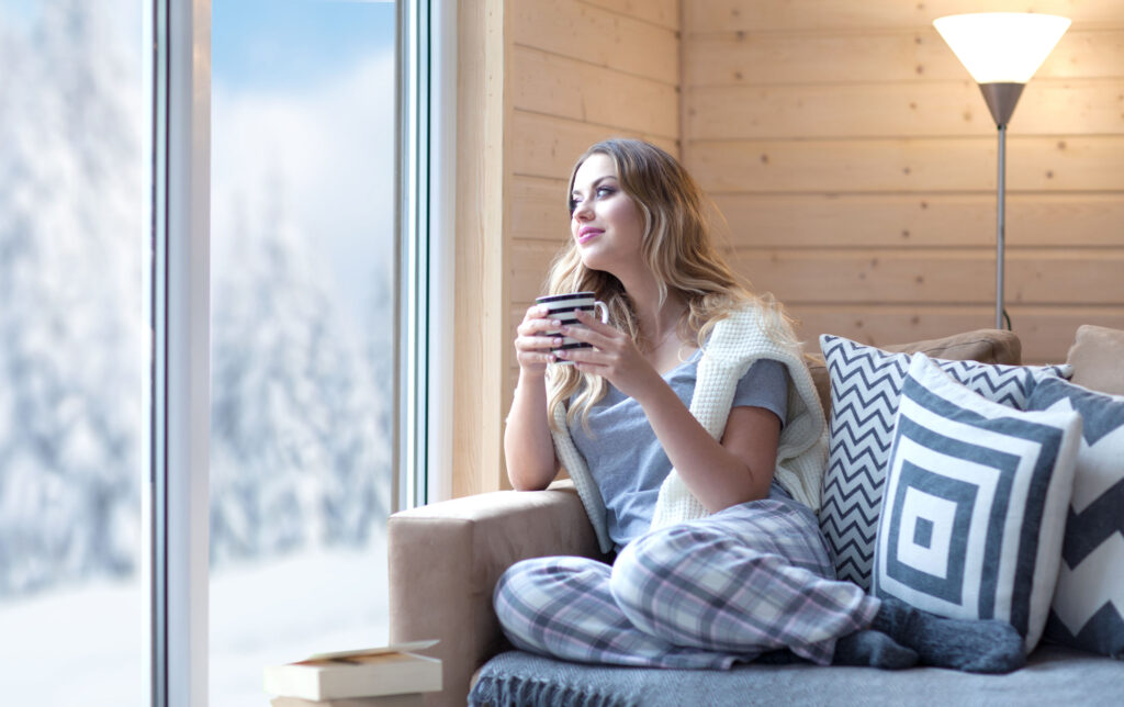 Woman enjoying cup of coffee inside in winter